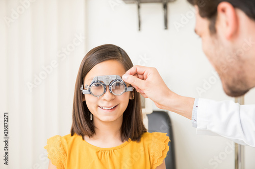 Cute girl wearing trial frame in ophthalmology clinic