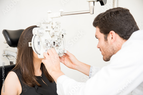 Fototapeta Naklejka Na Ścianę i Meble -  Optometrist and woman at eye examination with phoropter