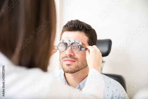 Fototapeta Naklejka Na Ścianę i Meble -  Optometrist taking eye test through trial frames at the clinic