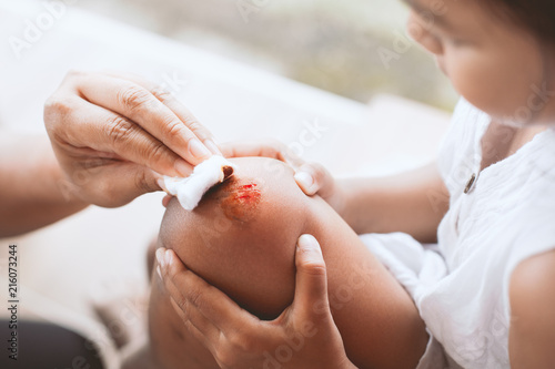 Parent helping her child perform first aid knee injury after she has been an accident