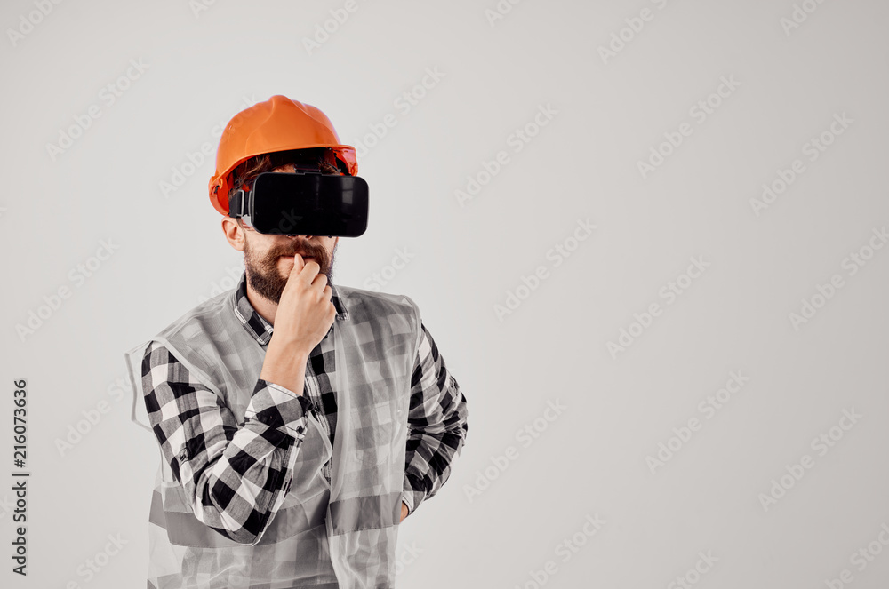 male builder in an orange helmet in 3D glasses virtual reality