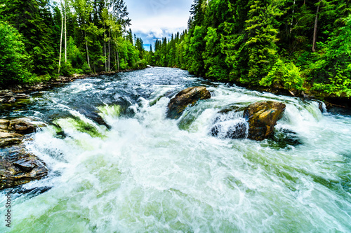 Large rocks split the water of the Murtle River as it drops over the Mushbowl Falls in Wells Gray Provincial Park in British Columbia, Canada photo