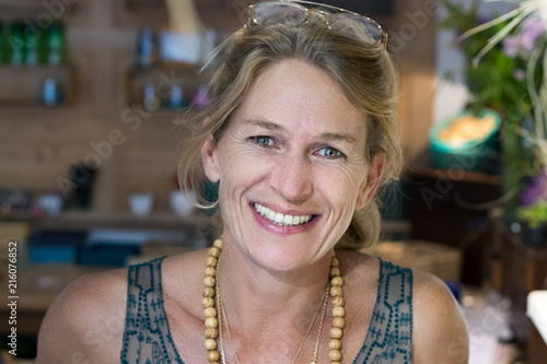 Portrait of a french blonde mature woman smiling at her store, entrepreneur concept.