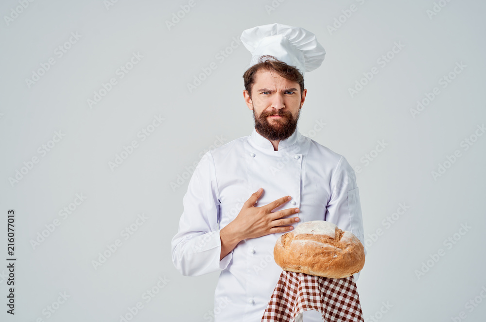the cook in work clothes and in a headdress holds a loaf of bread in her hand the cook in work clothes and in a headdress holds a loaf of bread in her hand