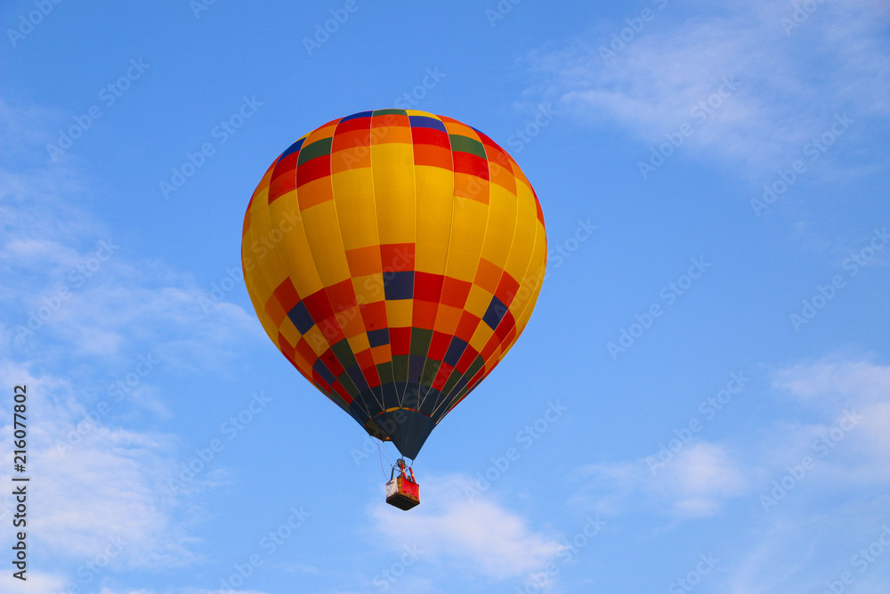 Naklejka premium colorful hot air balloon against blue sky. hot air balloon is flying in white clouds. beautiful flying on hot air balloon