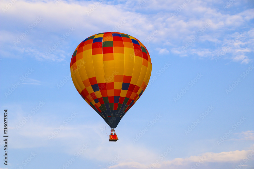 Naklejka premium colorful hot air balloon against blue sky. hot air balloon is flying in white clouds. beautiful flying on hot air balloon