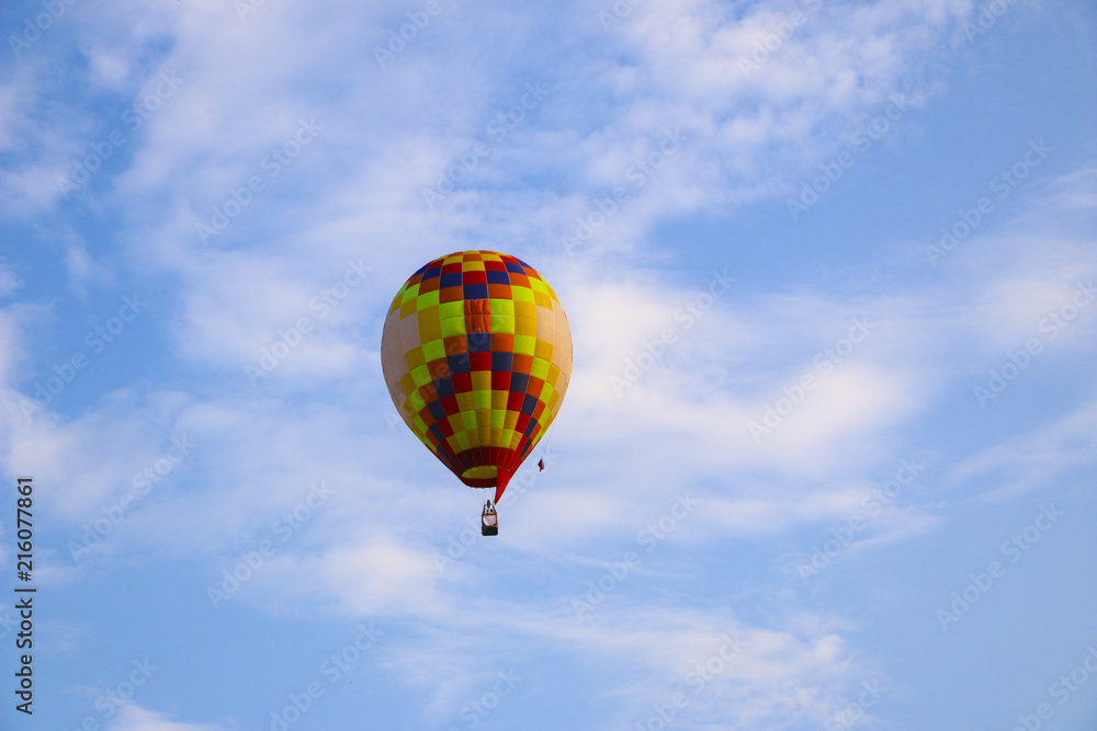 colorful hot air balloon against blue sky. hot air balloon is flying in white clouds. beautiful flying on hot air balloon colorful hot air balloon against blue sky. hot air balloon is flying in white clouds. beautiful flying on hot air balloon