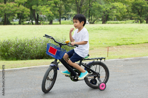 Asian cute boy ride a bicycle at park green nature background.Side view Image.