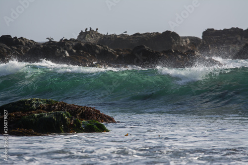 Clear big wave among rocks in water