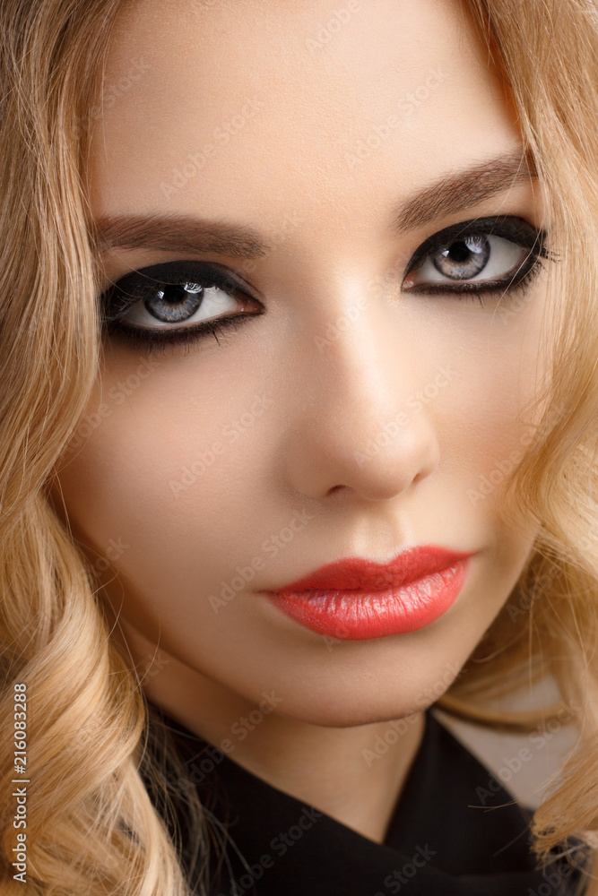 Glamour woman model with sexy evening make-up, curly blond hair, red lips and long eyeliner on eyes Glamour woman model with sexy evening make-up, curly blond hair, red lips and long eyeliner on eyes