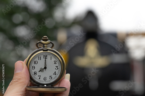 Clock with lid shows at 8 o'clock in hand on steam Locomotives blurred background.