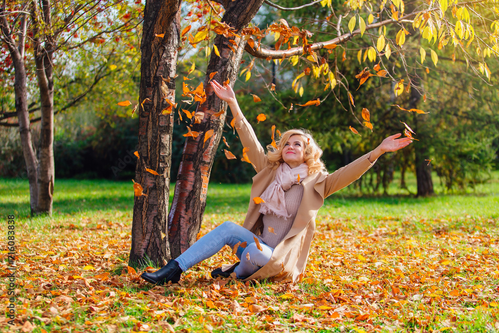 Young beautiful woman throwing up fallen autumn leaves over her head Young beautiful woman throwing up fallen autumn leaves over her head