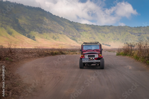 Red jeep car driving on the sand road near Savana land in Bromo Tengger Semeru national park, East Java, Indonesia © sirintra