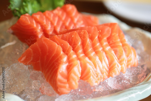 Salmon raw sashimi on ice Japanese traditional dish on wooden table.