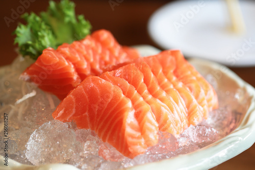 Salmon raw sashimi on ice Japanese traditional dish on wooden table.
