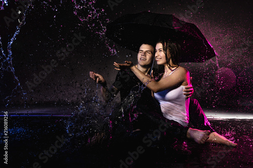 Couple young Teens together in small pool, drops of water and colored light