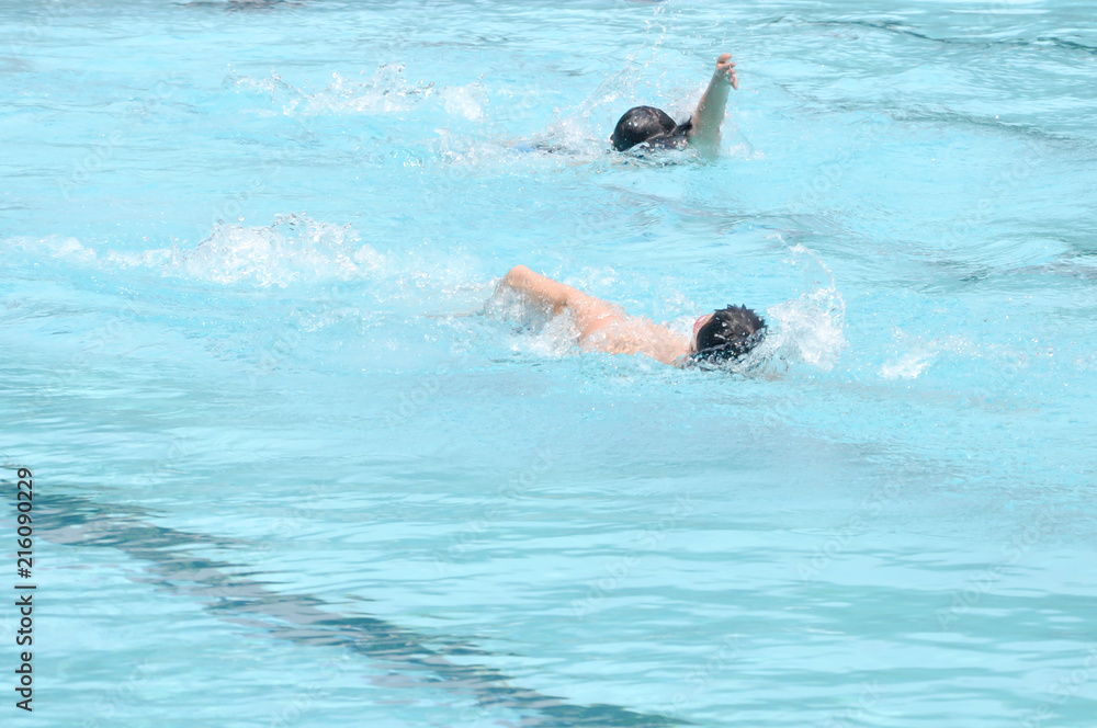 young man swim crawl style in outdoor swimming pool