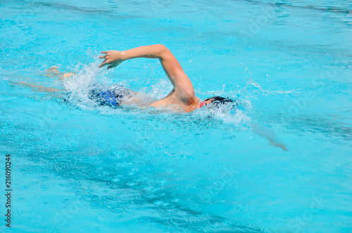 young man swim crawl style in outdoor swimming pool