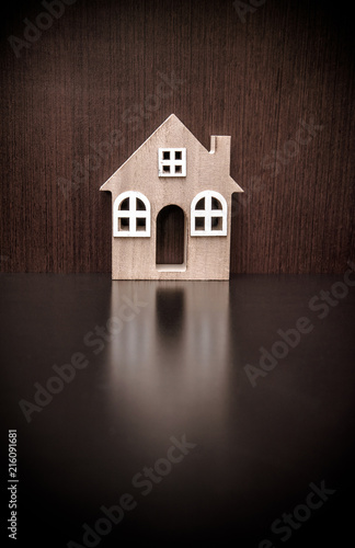 The symbol of the house stands on a brown wooden background 