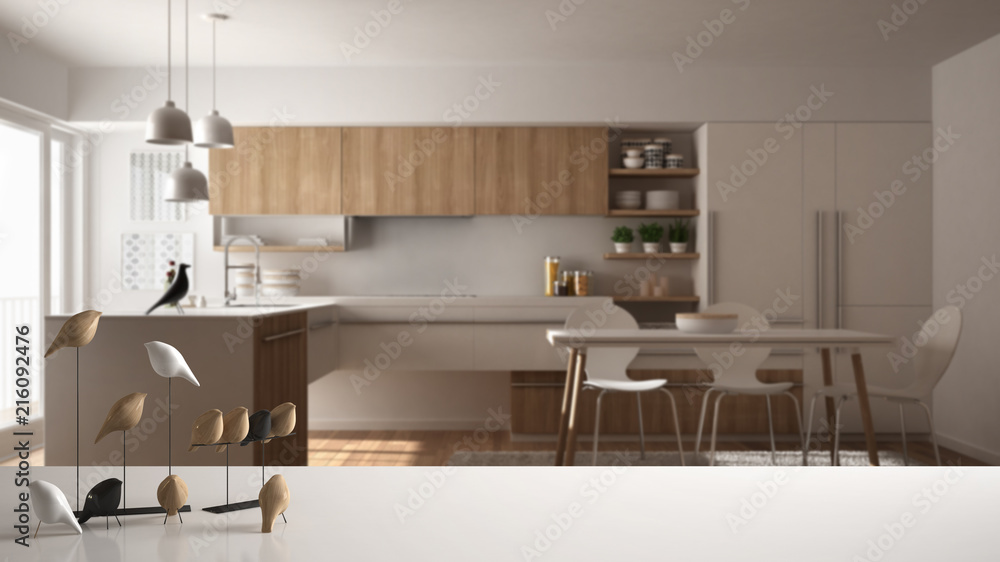 White table top or shelf with minimalistic bird ornament, birdie knick - knack over blurred contemporary wooden kitchen, modern interior design White table top or shelf with minimalistic bird ornament, birdie knick - knack over blurred contemporary wooden kitchen, modern interior design