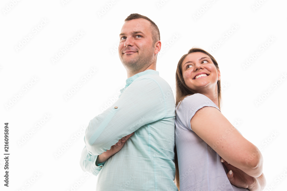 Low angle of young happy couple standing back to back Low angle of young happy couple standing back to back