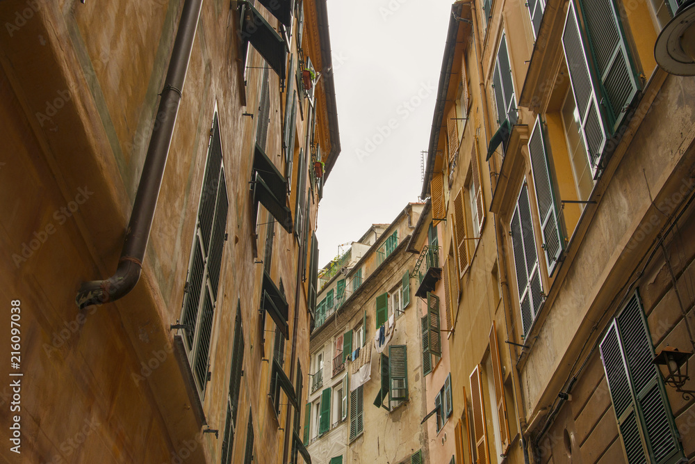 View at traditional style buildings with hanging wardrobe bellow the windows in historic center of Genoa, Italy