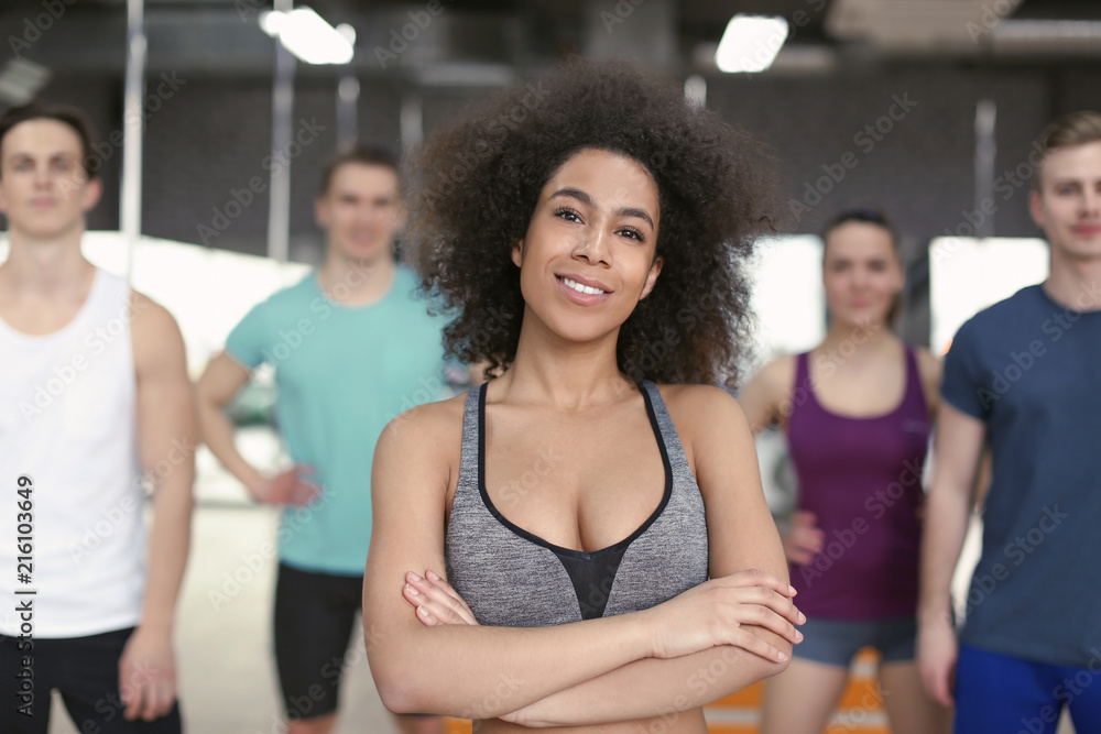 Sporty girl with group of athletes in gym