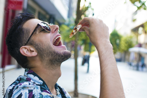 young eating portion of outdoor pizza in the city