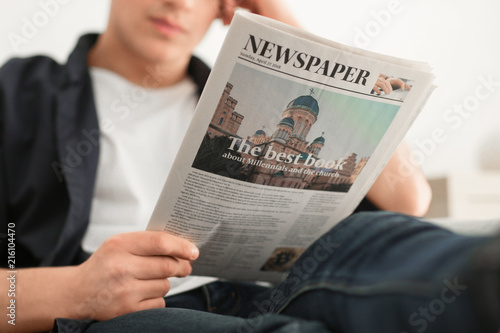 Young man reading newspaper...