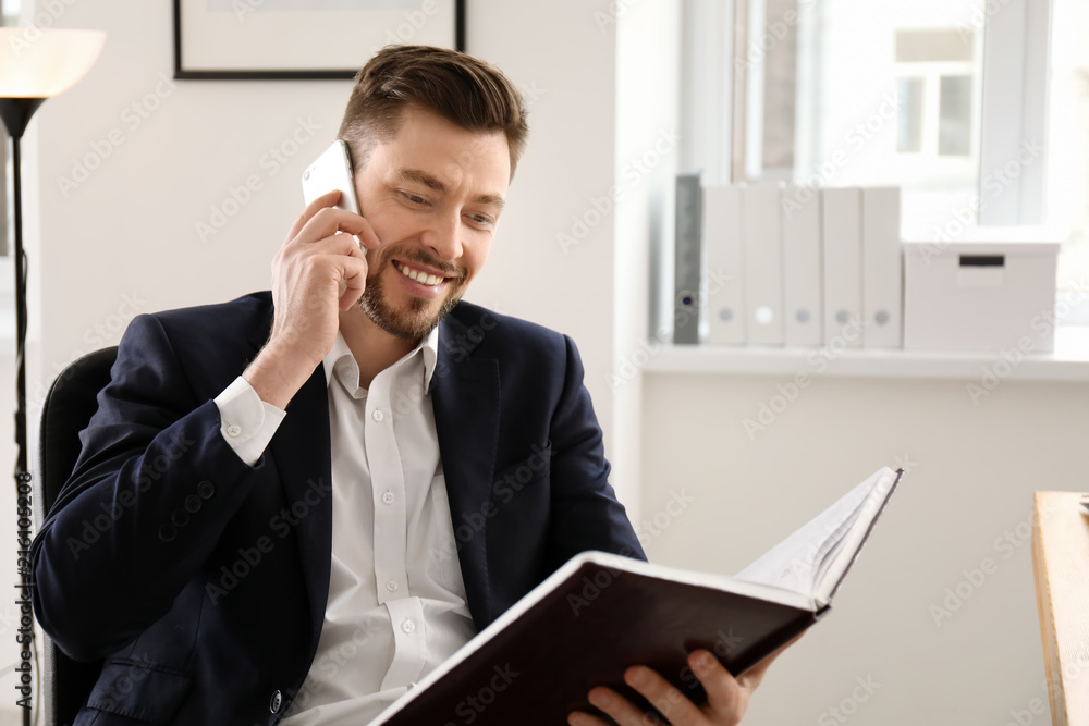 Businessman talking on phone while working in office Businessman talking on phone while working in office