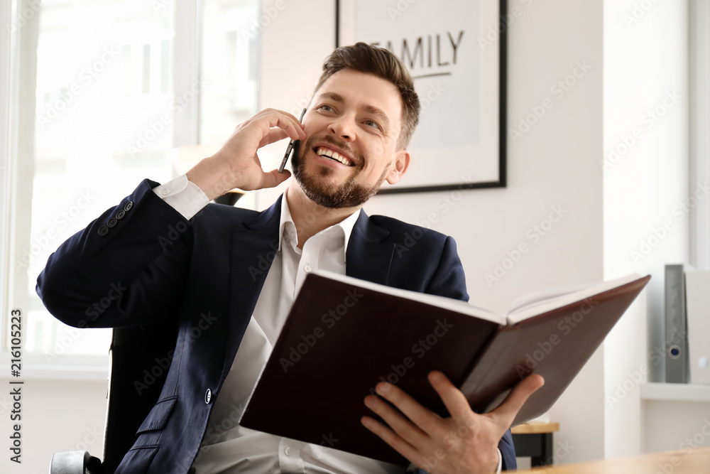 Businessman talking on phone while working in office Businessman talking on phone while working in office