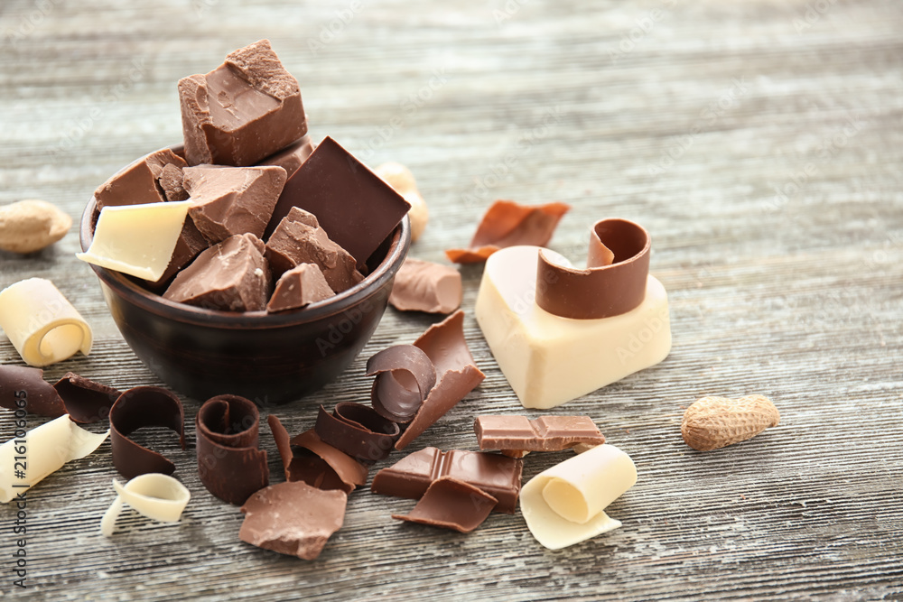 Bowl with pieces of chocolate and curls on wooden table Bowl with pieces of chocolate and curls on wooden table