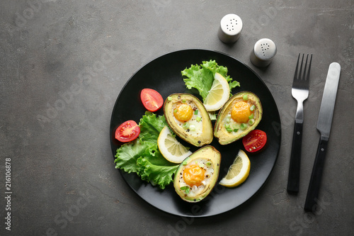 Plate with tasty eggs baked in avocado on table