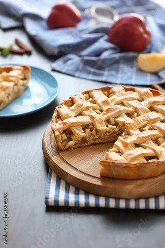 Wooden board with tasty homemade apple pie on table