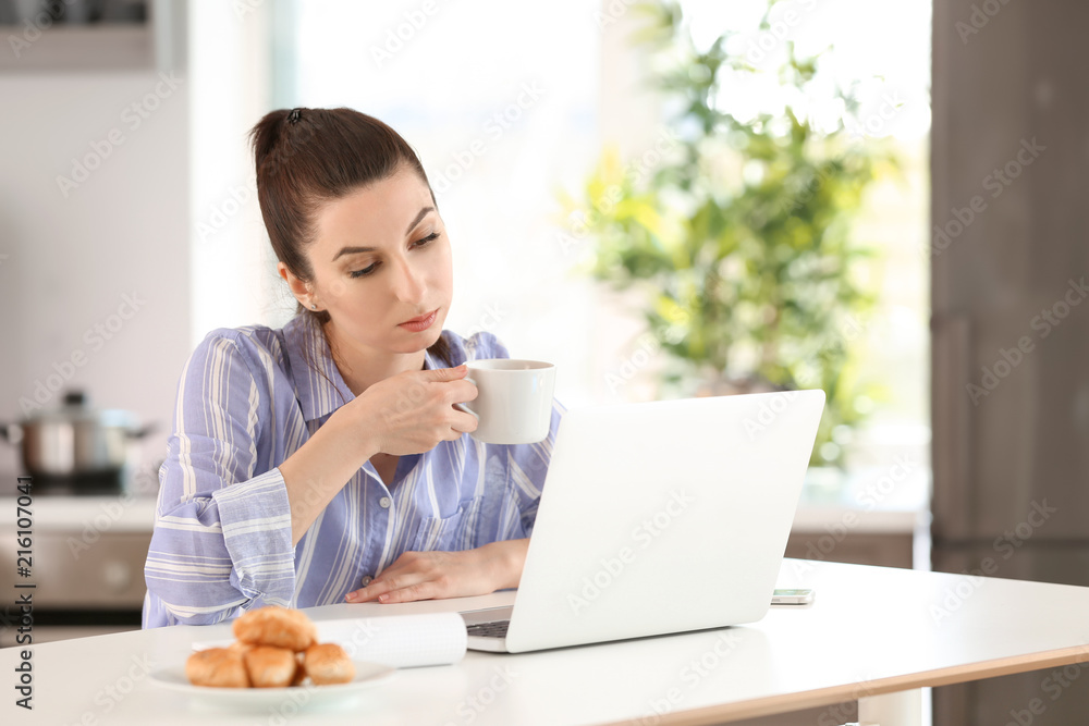 Young female freelancer drinking coffee while working with laptop at home Young female freelancer drinking coffee while working with laptop at home