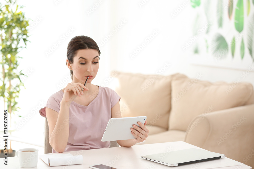 Young female freelancer working with tablet computer at home