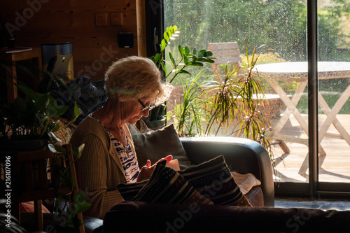 elderly woman reads a book sitting in the sofa