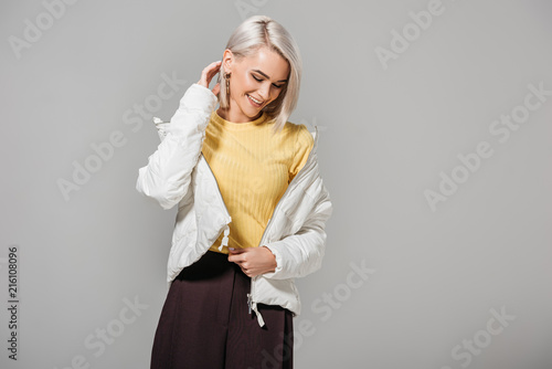 smiling female model in stylish outfit posing isolated on grey background