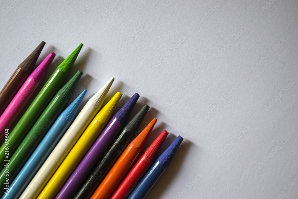 Multicolored pencils on white background. A palette of pencils on a table, close up. Multicolored pencils on white background. A palette of pencils on a table, close up.