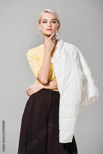 stylish female model posing with jacket over shoulder isolated on grey background