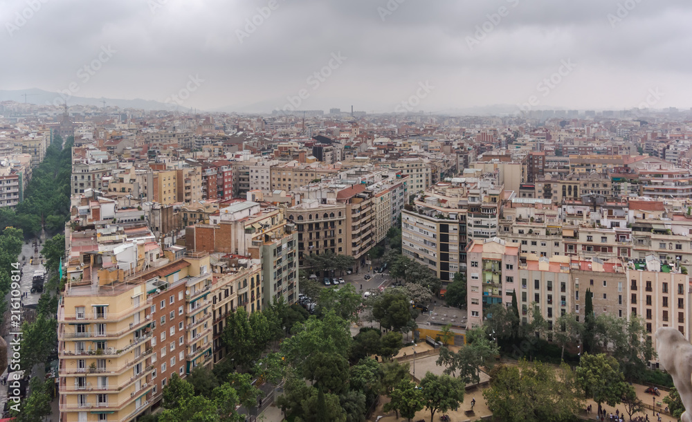 View to Barcelona city from the top of the basilica in a dull, murky day with a very grey and overcast sky. Barcelona skyline under heavy grey clouds.