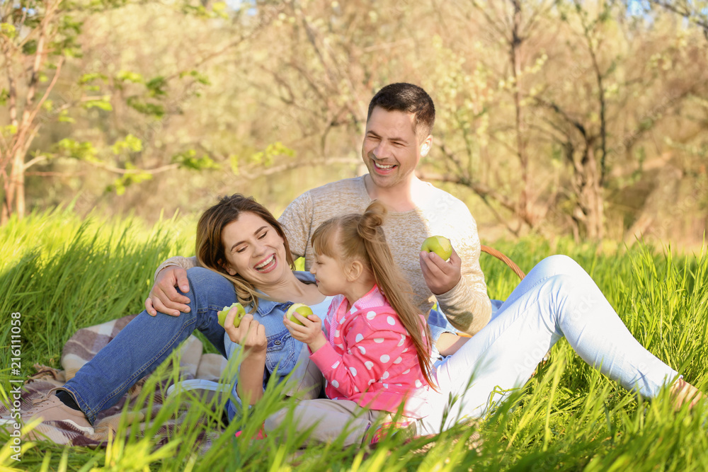 Fototapeta premium Happy family eating apples in park