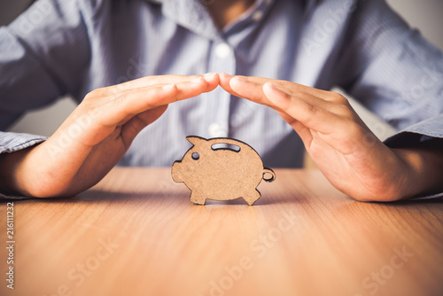 Hand protecting the icon piggy bank - the concept of insurance for Deposit photo