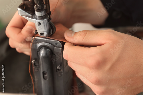 Man using sewing machine in leather workshop, closeup