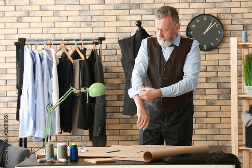 Mature tailor working in at...