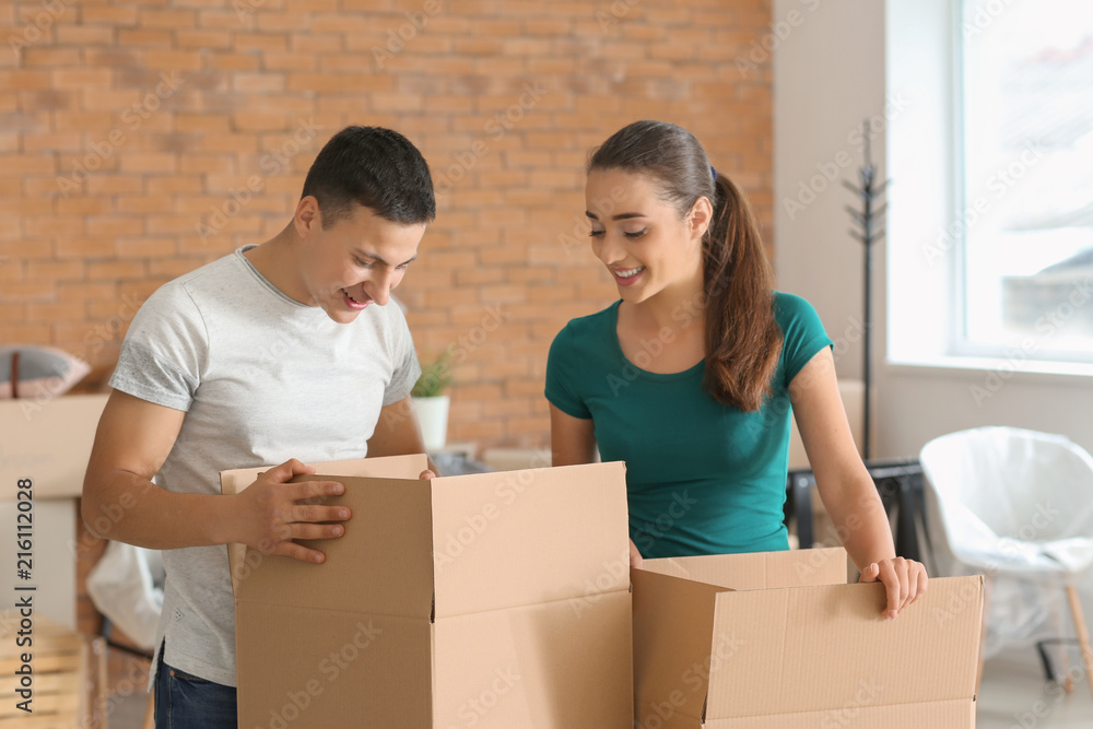 Young couple with boxes indoors. Moving into new house Young couple with boxes indoors. Moving into new house