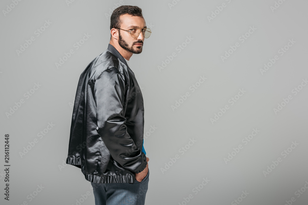 Fototapeta premium confident handsome man in stylish black bomber isolated on grey background