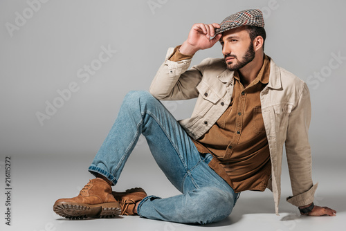 handsome man posing in corduroy shirt and autumn tweed cap, on grey photo