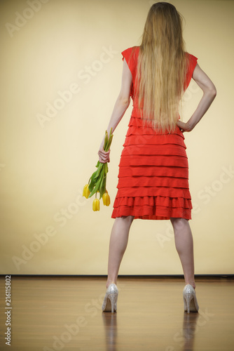 woman with yellow tulips bunch, back view