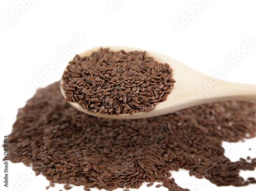 Flax seeds in a wooden spoon on white isolated background